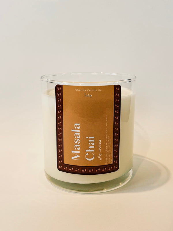 A white candle in a glass jar with a brown label